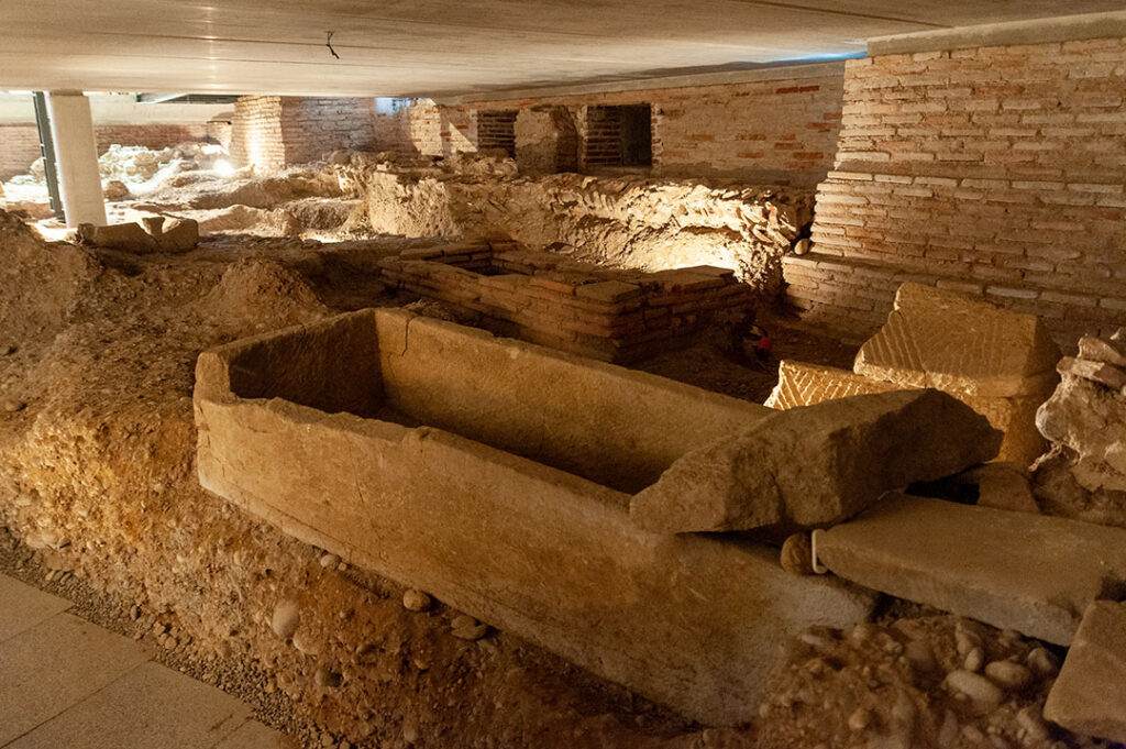Vue de la crypte archéologique de Saint-Pierre-des-cuisines. Sous le sol de l'église, on peut voir des vestiges de l'ancienne église : des murs et des sarcophages en calcaire ou marbre.
