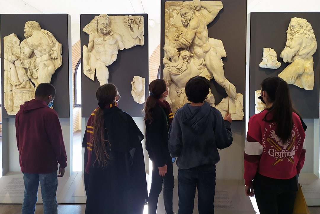 Un groupe d'élèves devant les reliefs des travaux d'Hercule