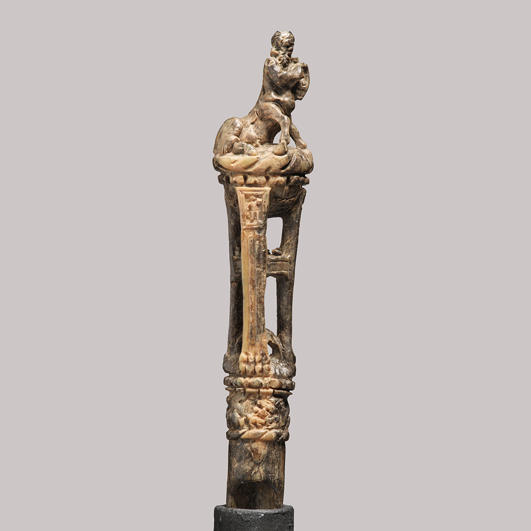 Manche d'ustensile décoré d'une représentation de centaure, assis sur un trépied et jouant de la lyre. L'objet est fabriqué en ivoire d'éléphant.