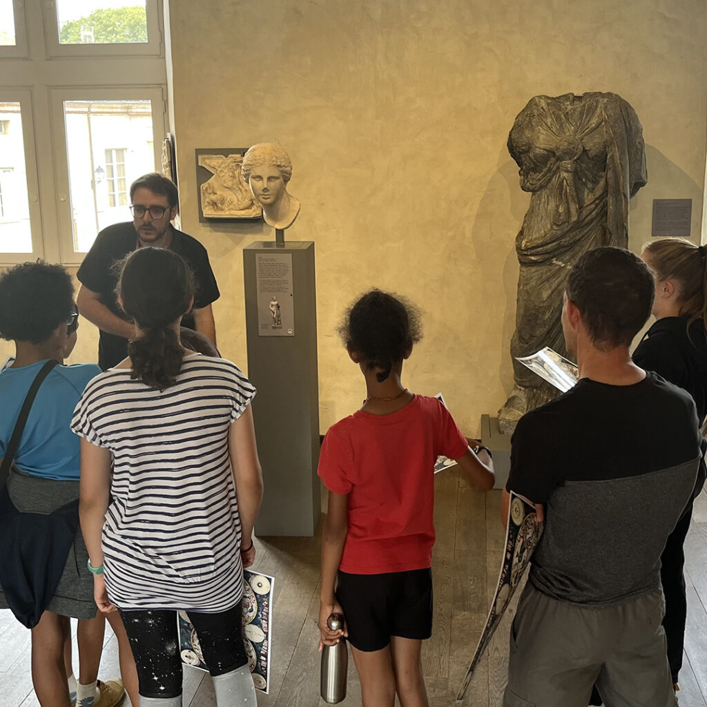 Un groupe de visiteurs et un médiateur autour d'une sculpture représentant Vénus.
