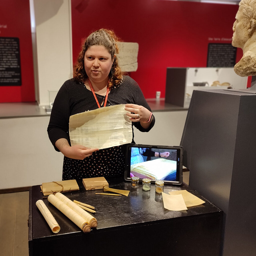 Une médiatrice culturelle montre des outils utilisés pour l'écriture dans l'Antiquité