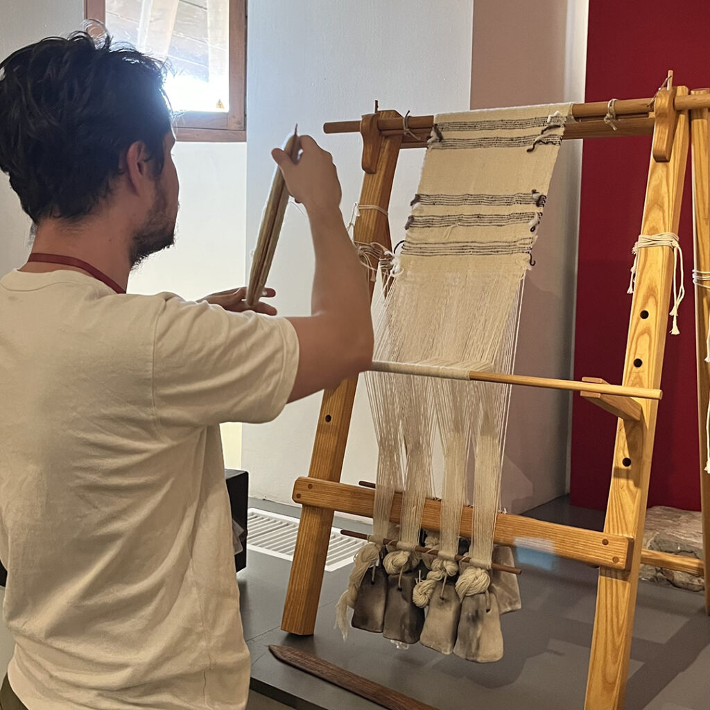 Un médiateur culturel montre l'usage d'un métier à tisser antique