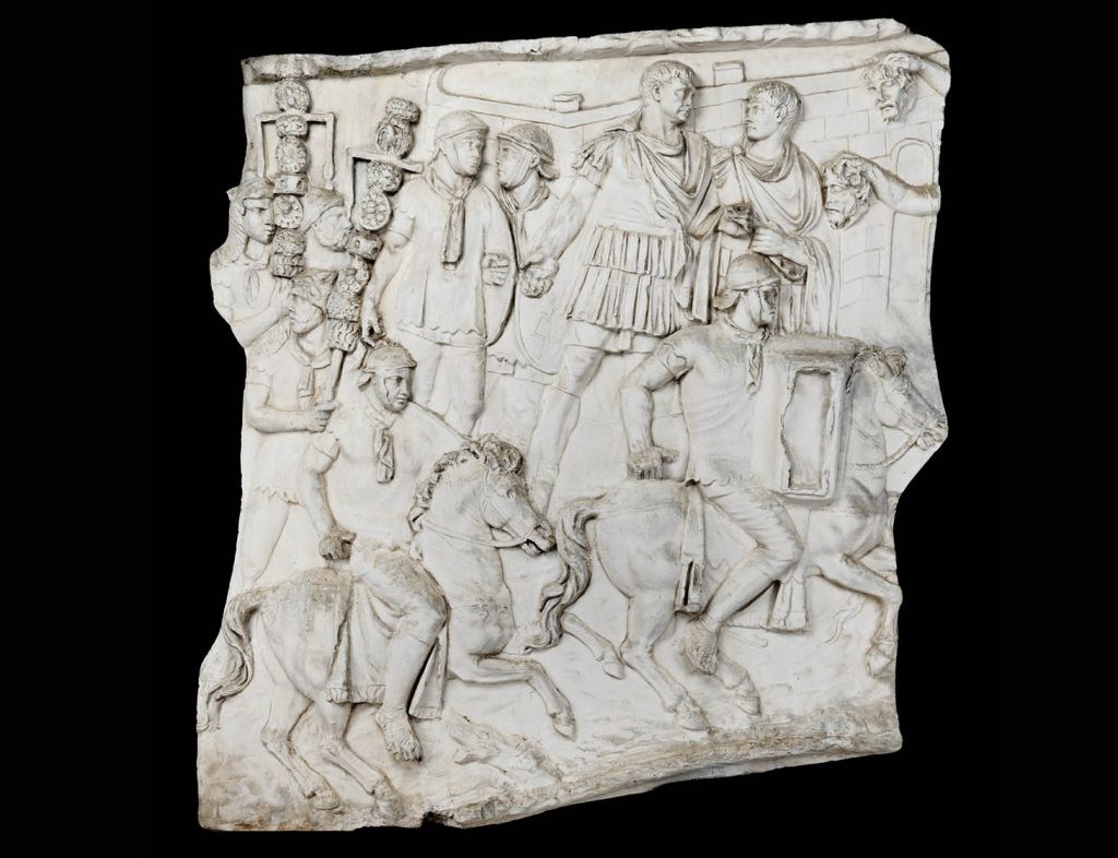 Détail d'un relief sculpté montrant une scène de parade guerrière.